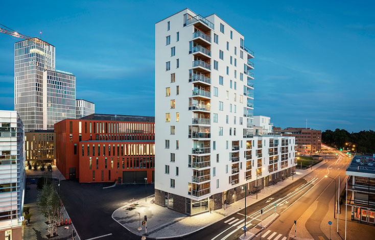 Modern high-rise apartment building with balconies, surrounded by urban streets and cityscape.