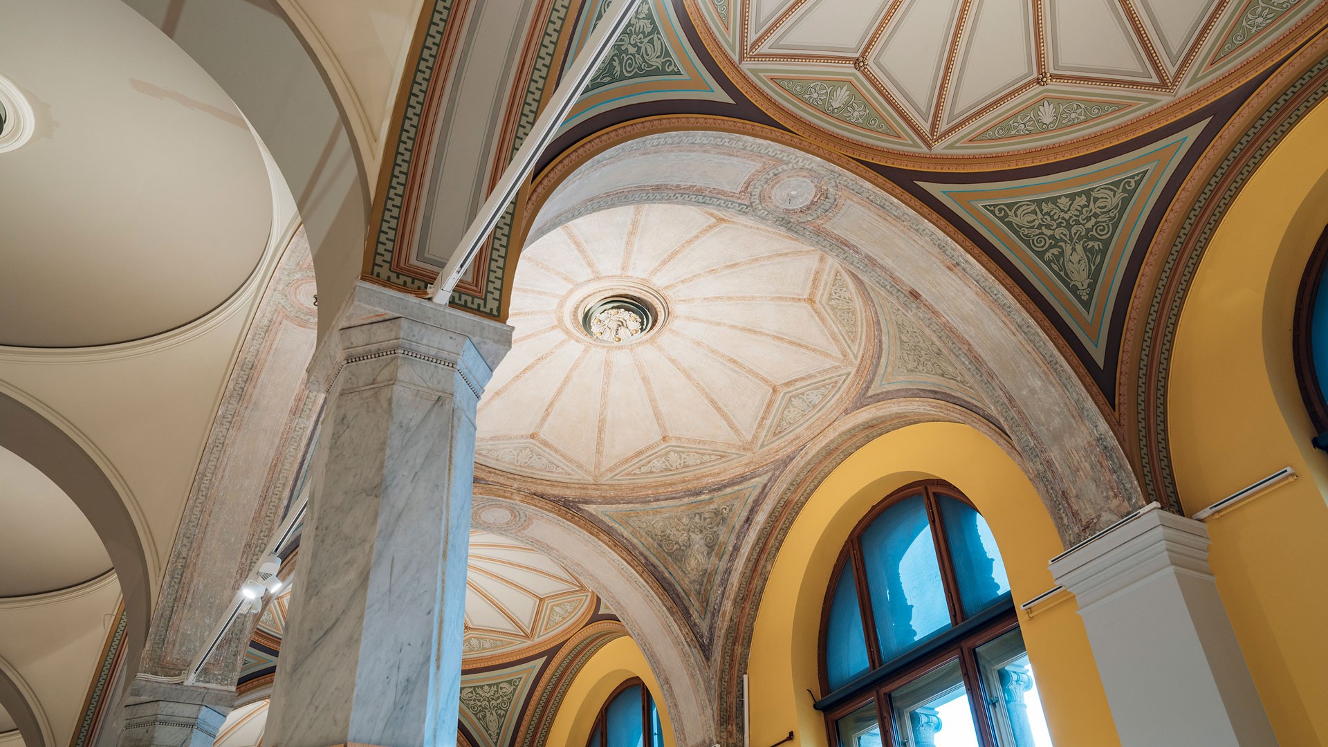 Ornate vaulted ceilings with detailed frescoes and arches in a historic architectural setting.
