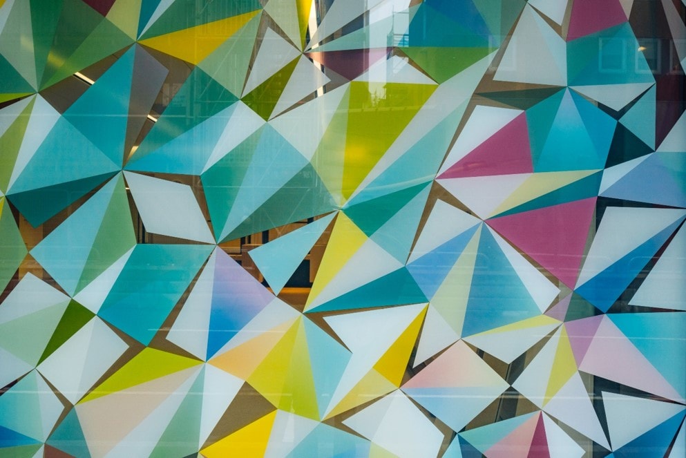 Colorful geometric pattern with overlapping triangles in shades of blue, yellow, and pink.