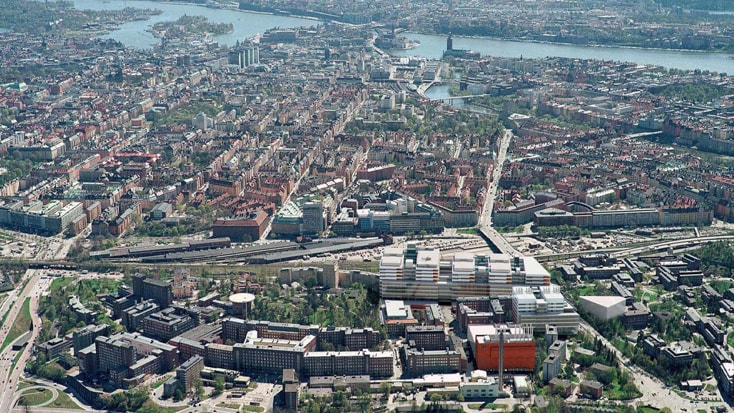 Aerial view of a cityscape with dense urban buildings, roads, and a river running through the city.