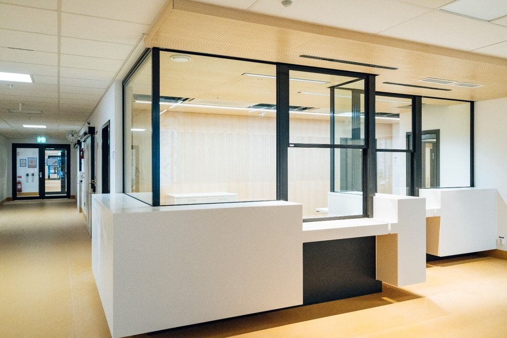 Modern reception area with large glass windows and white counters in a bright hallway setting.