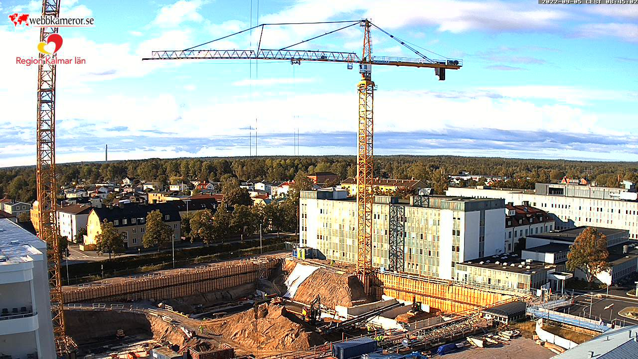 The construction site with a large crane in the center of the image.