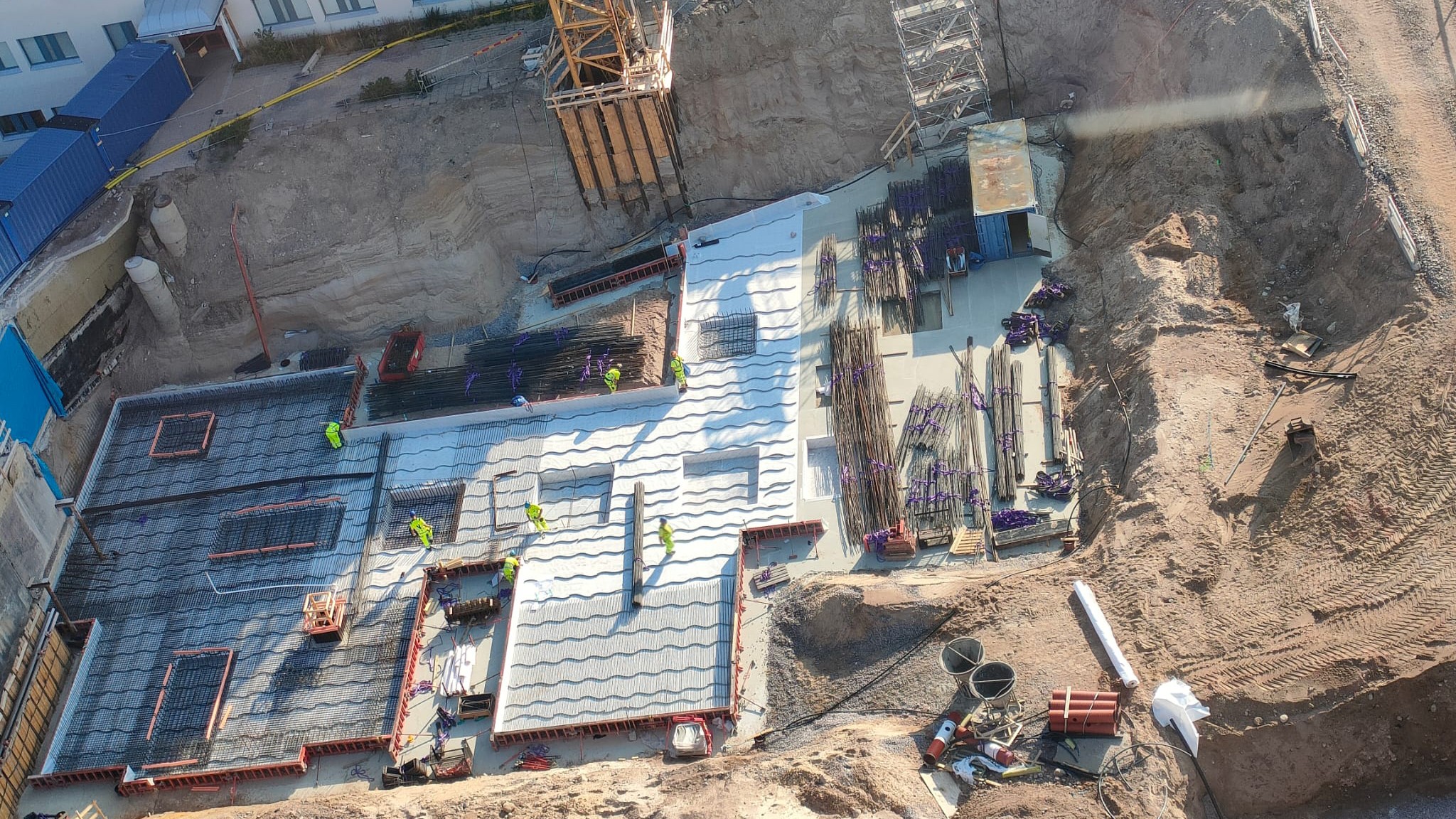 The construction site from above. Construction workers in yellow clothes at work.