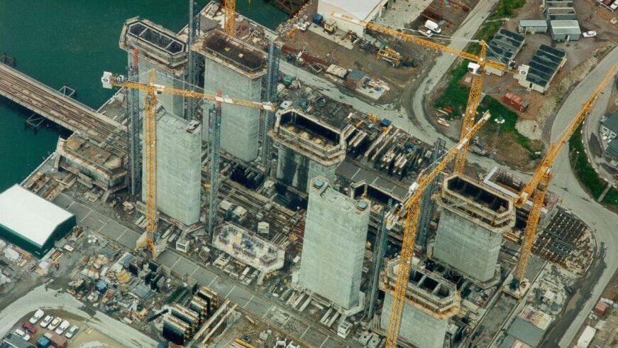 The Öresund Bridge Aerial view of a construction site with multiple cranes and tall concrete structures near water.