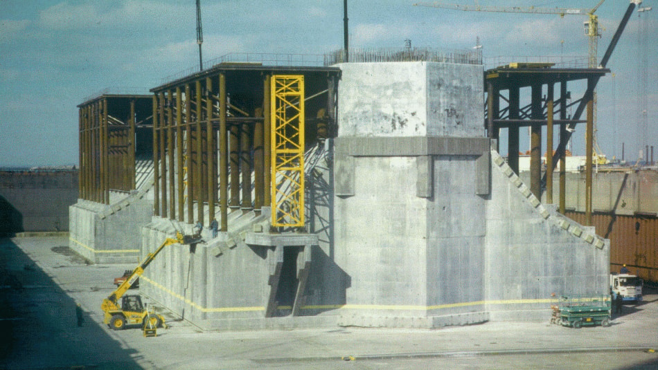 The Öresund Bridge Construction site with large concrete structures, metal framework, cranes, and construction vehicles.