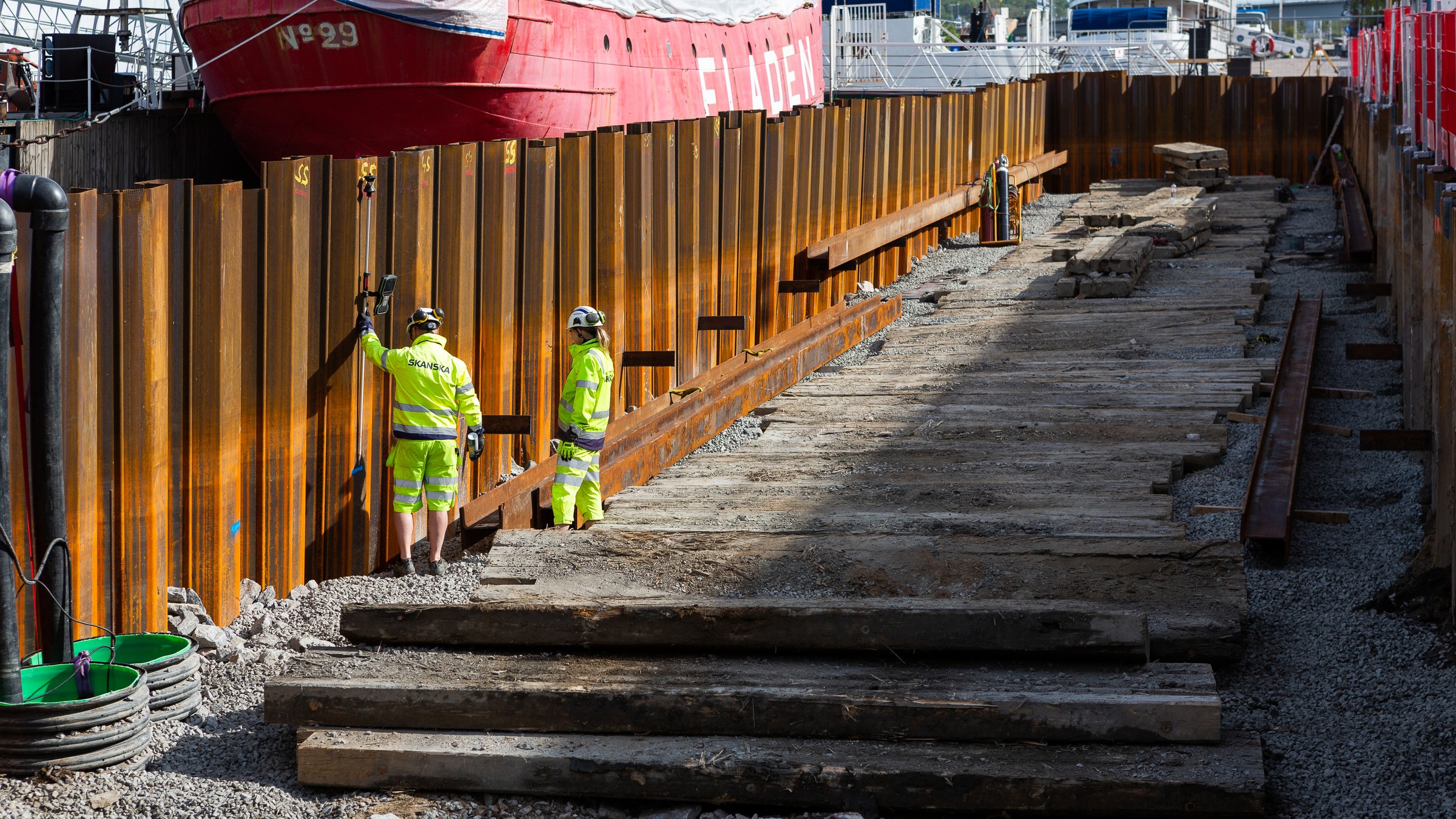 Two construction workers working on the river edge protection.