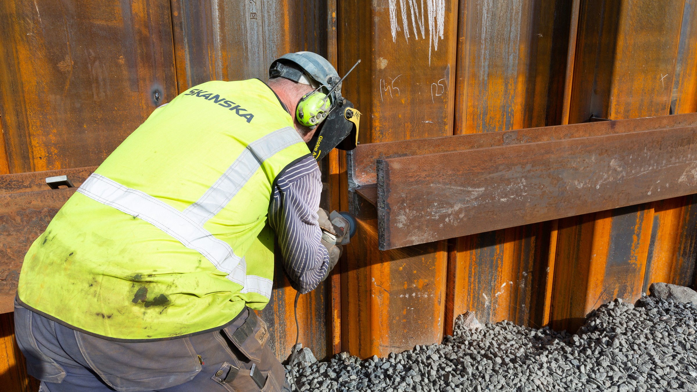 A construction worker is welding the river edge protection.