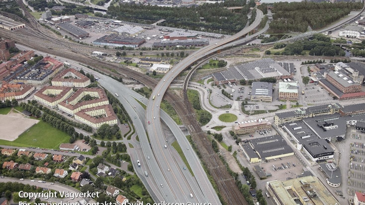 Partihallsförbindelsen Bridge Aerial view of a highway bridge crossing over railway tracks, surrounded by urban buildings and greenery.