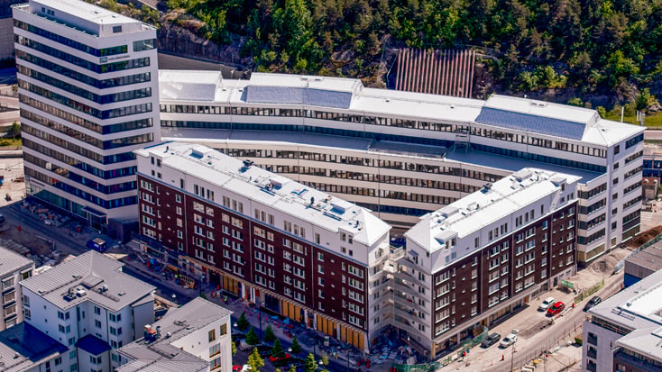 Aerial view of modern, curved residential complex surrounded by trees and urban landscape.