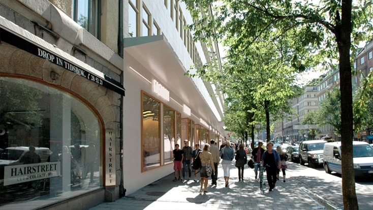 Bustling city street with pedestrians, Hairstreet salon, and modern building under leafy trees.