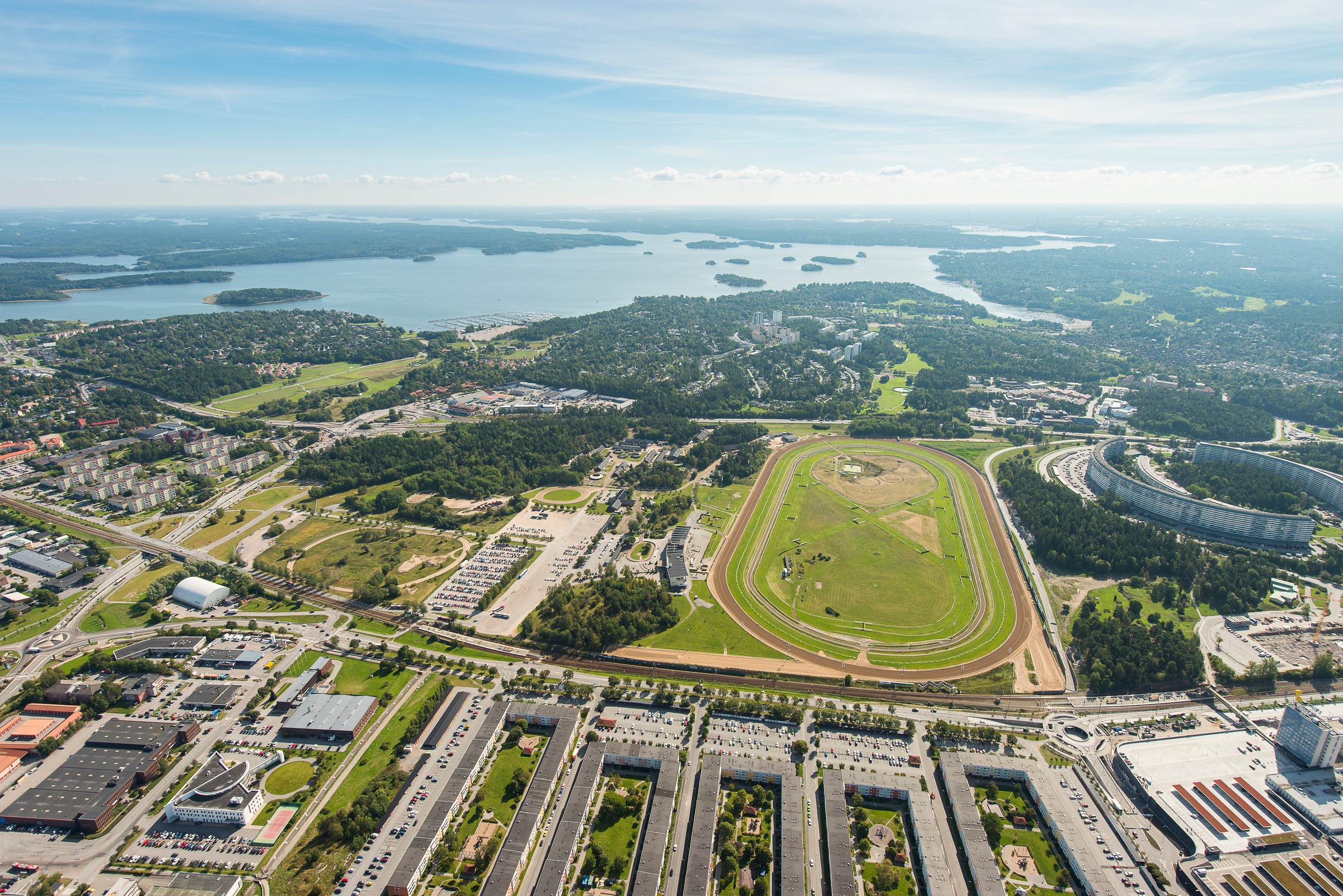 Täby Park is built around the former horse racing track in Täby. Aerial view of Stockholm's Solvalla racetrack with surrounding urban landscape and waterways.