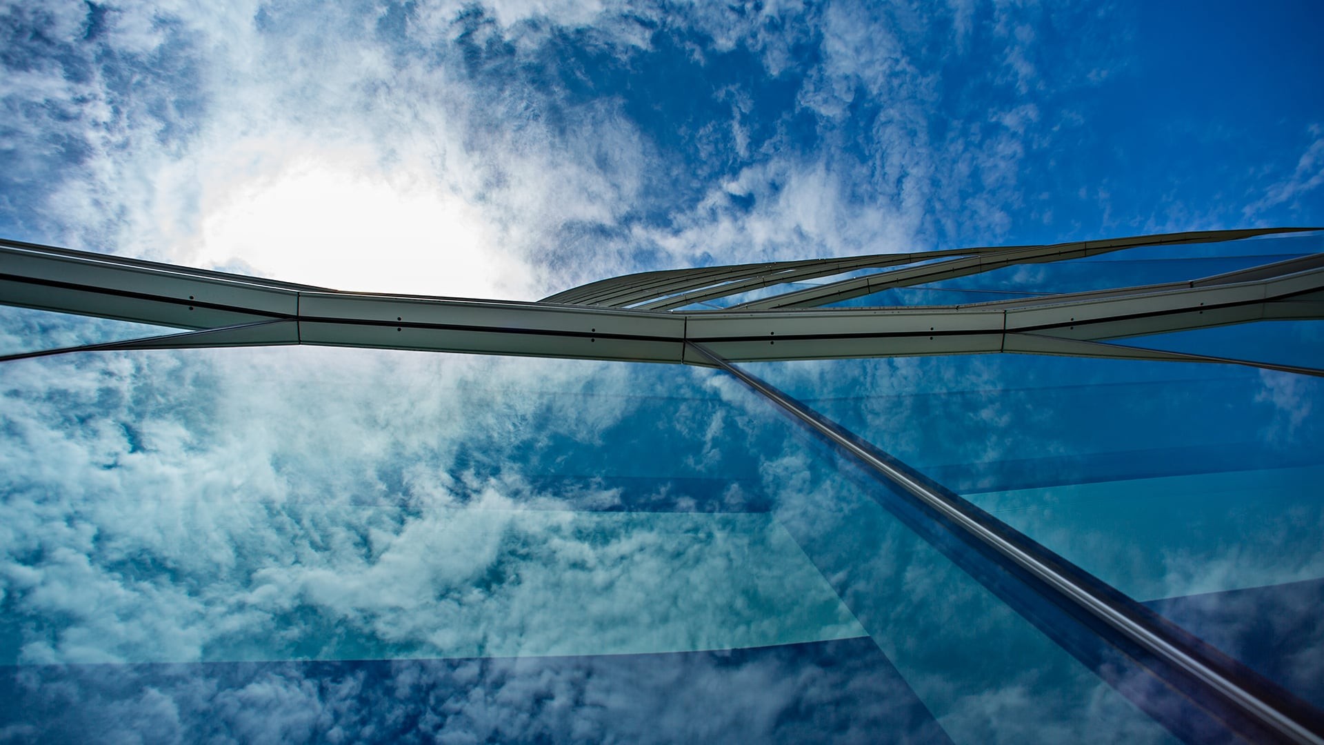 121 Seaport building reflecting a vibrant blue sky with scattered clouds.