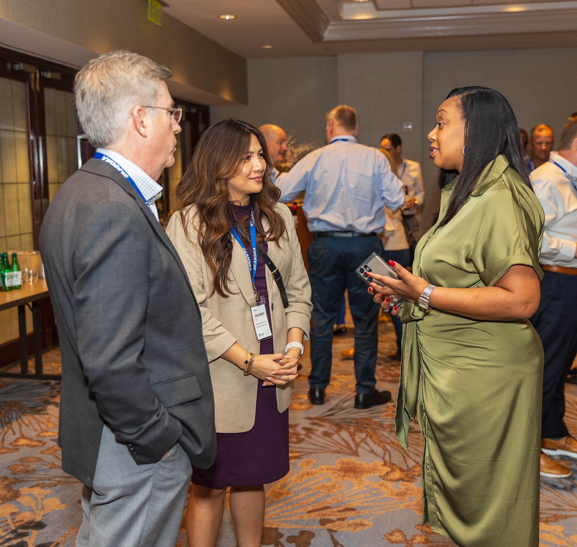 Three professionals in business attire engaging in conversation at a networking event.
