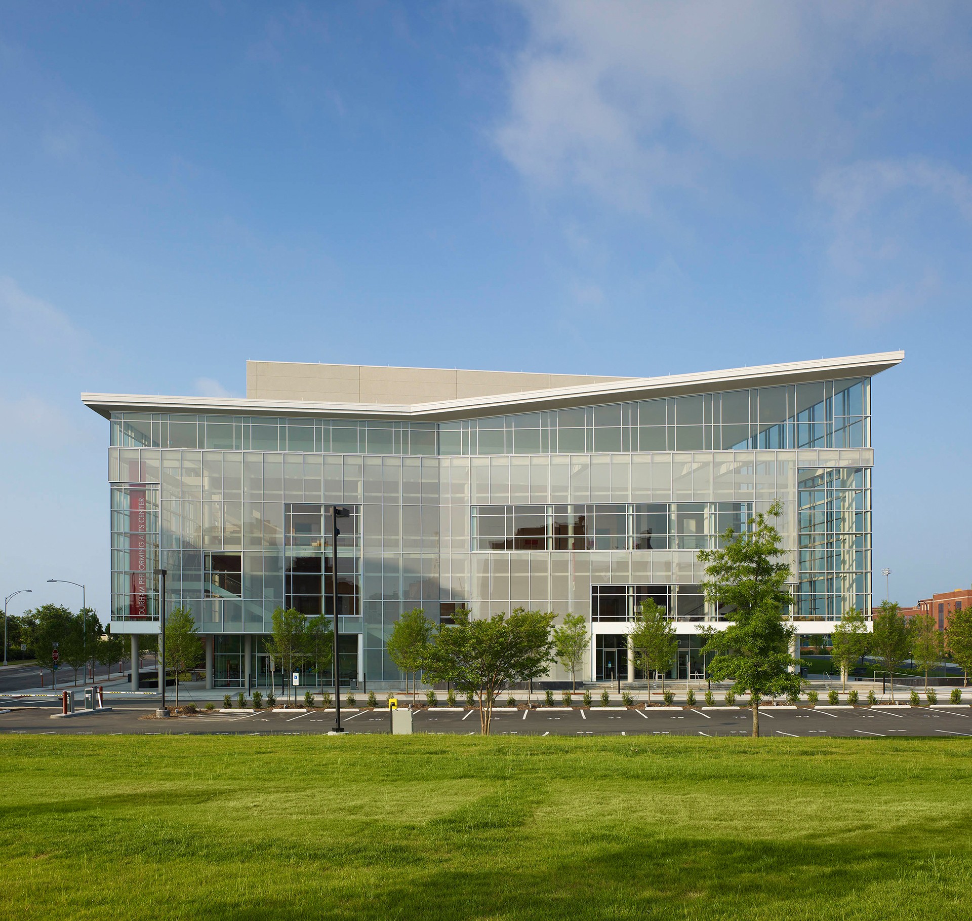 Modern Glass Office Building with Green Lawn and Clear Sky Modern glass office building with a green lawn and clear blue sky background.