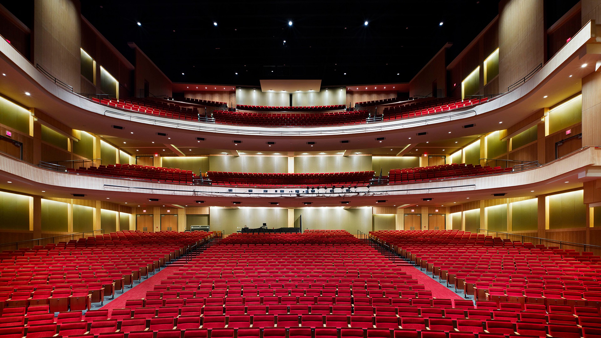 Interior view of a large modern theater with red seats and multiple balconies.