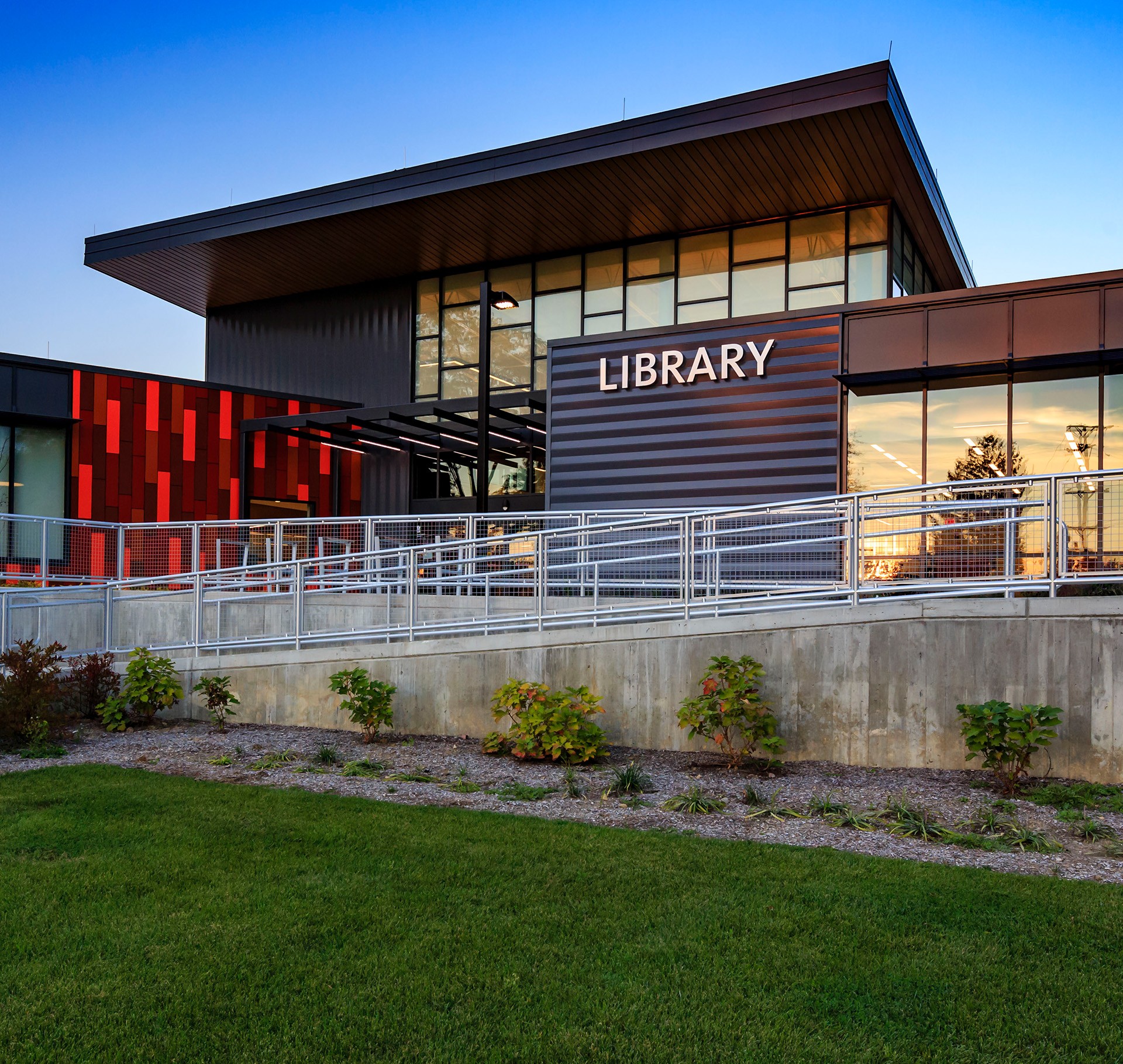 Modern library building design with green accents, large windows, and a flat roof.