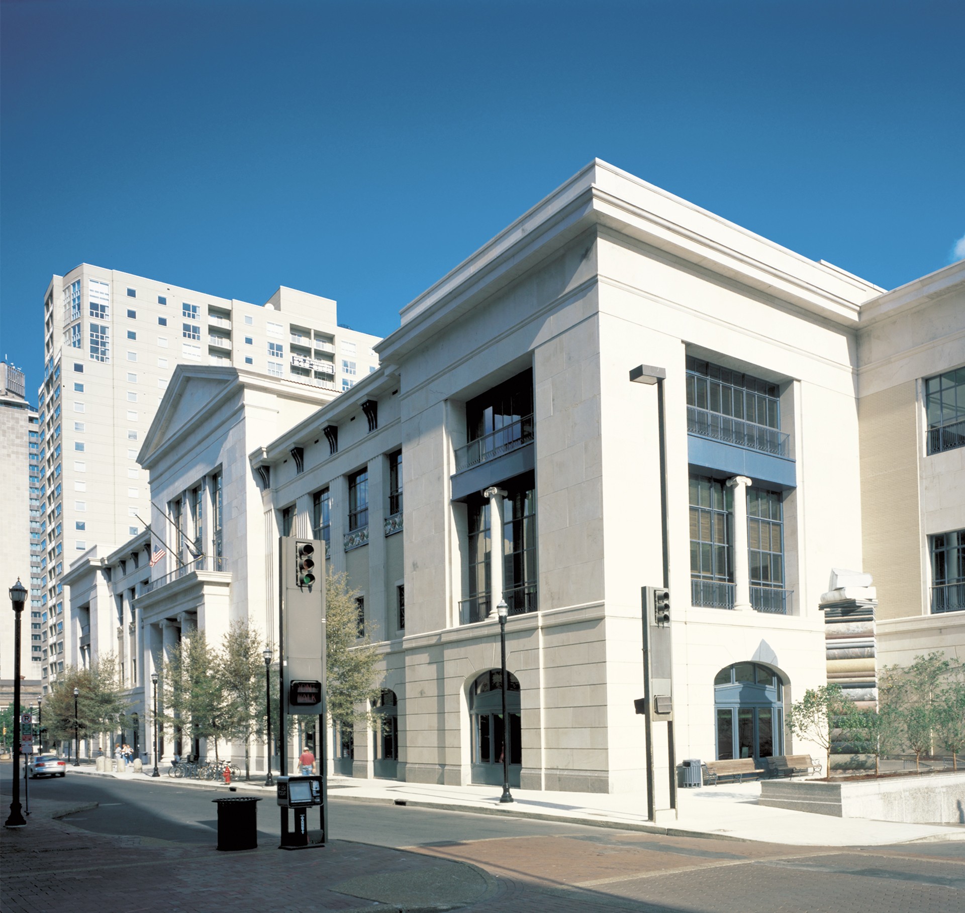 Modern urban building with large windows and columns, set against a clear blue sky.