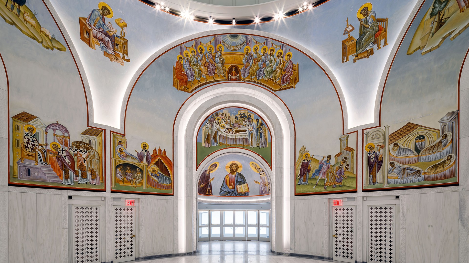 Interior of a church with colorful religious frescoes and bright overhead lighting.