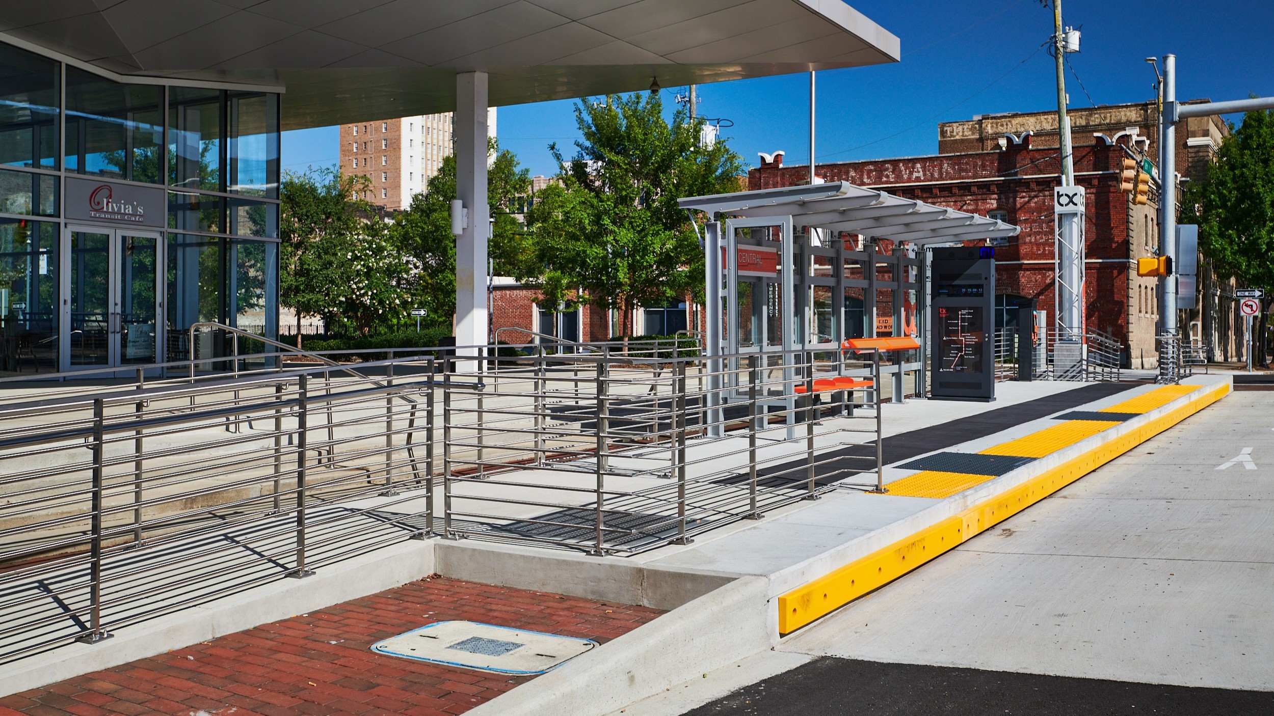 Modern outdoor bus stop with shelter, benches, and clear blue sky in an urban setting.