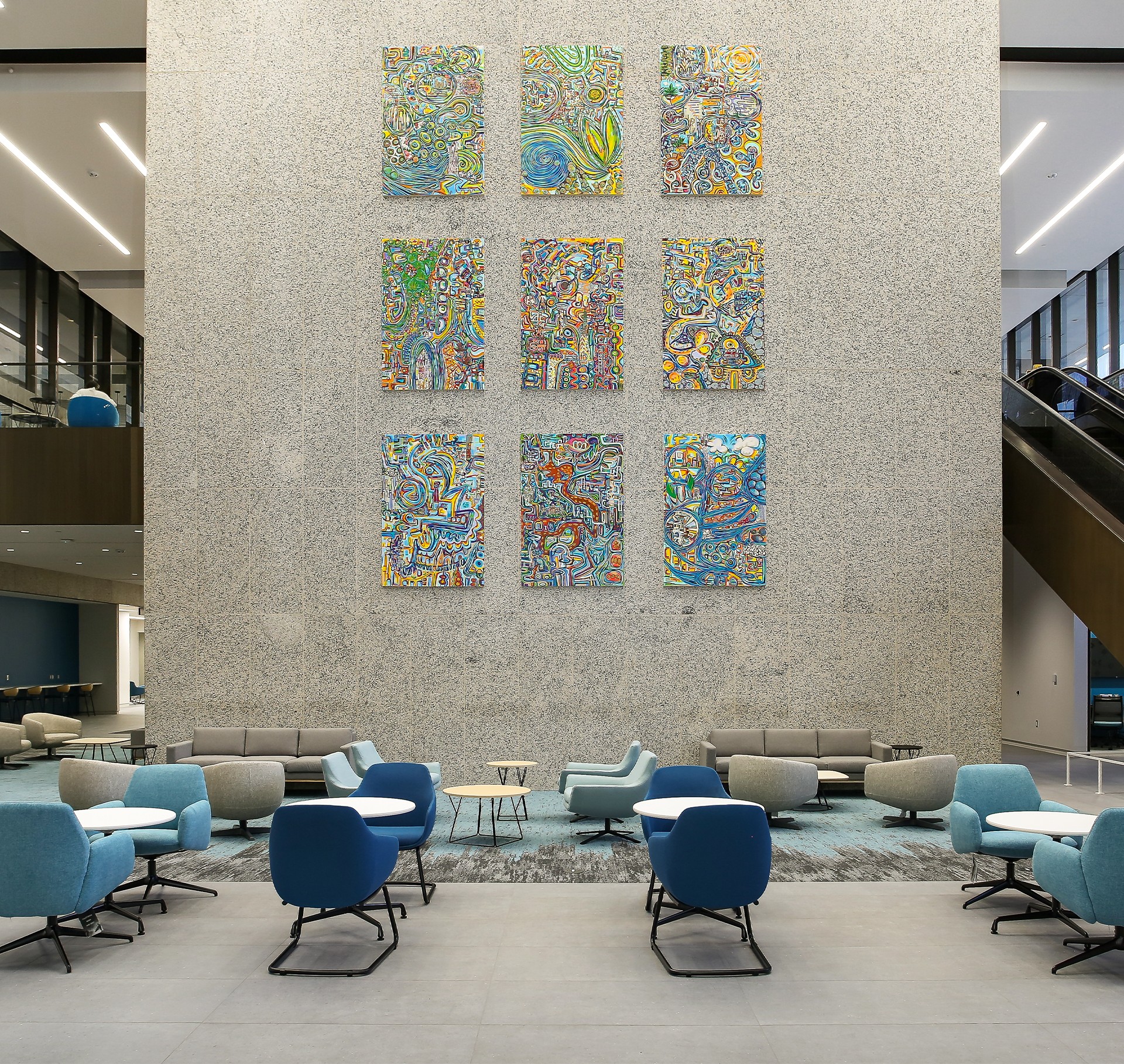 Modern Office Lounge with Colorful Abstract Wall Art Display Modern office lounge with blue chairs, abstract colorful wall art, and gray sofas.