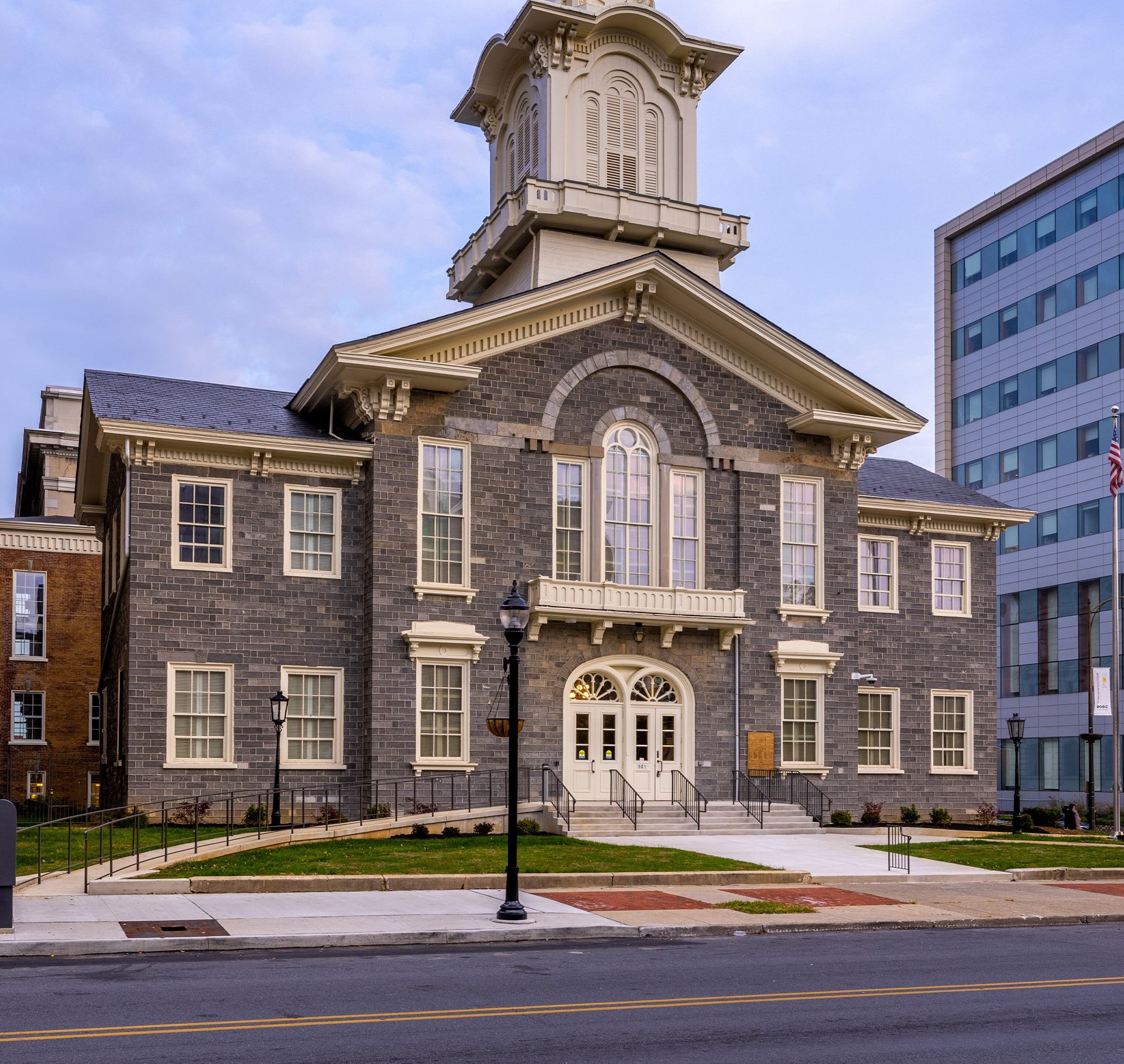 Historic gray brick courthouse with white trim and a clock tower under a blue sky.