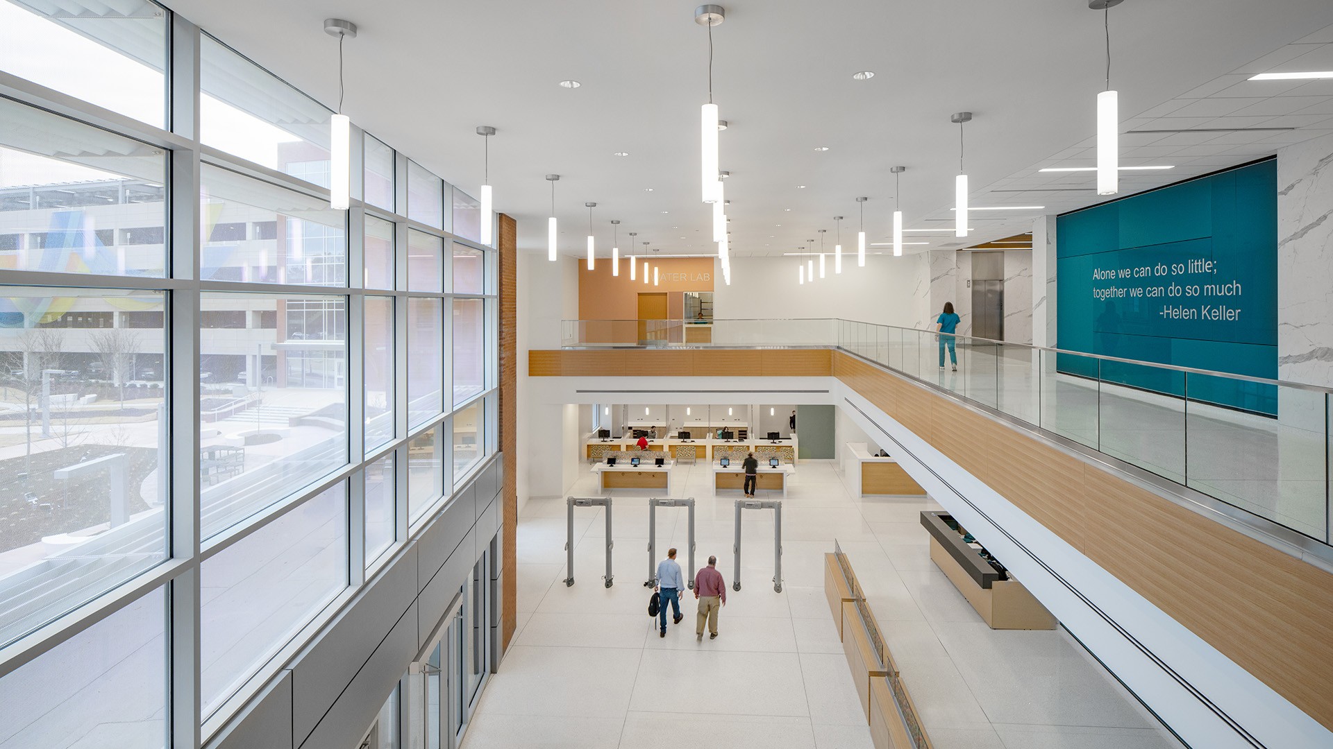 Modern bright airport security checkpoint with large windows and passengers walking.