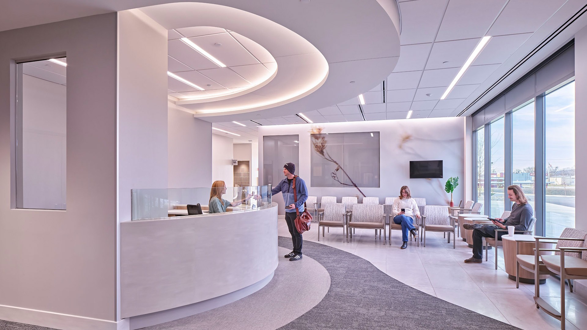 Modern medical office reception area with staff and patients in a bright waiting room.