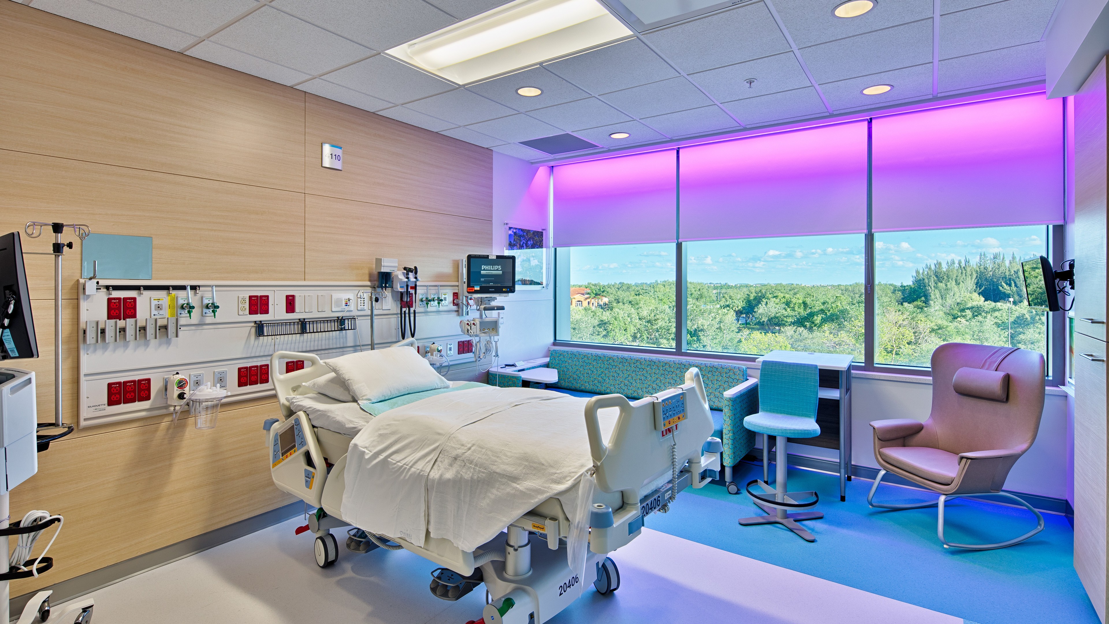 Modern hospital room with a patient bed, medical equipment, and large window view.