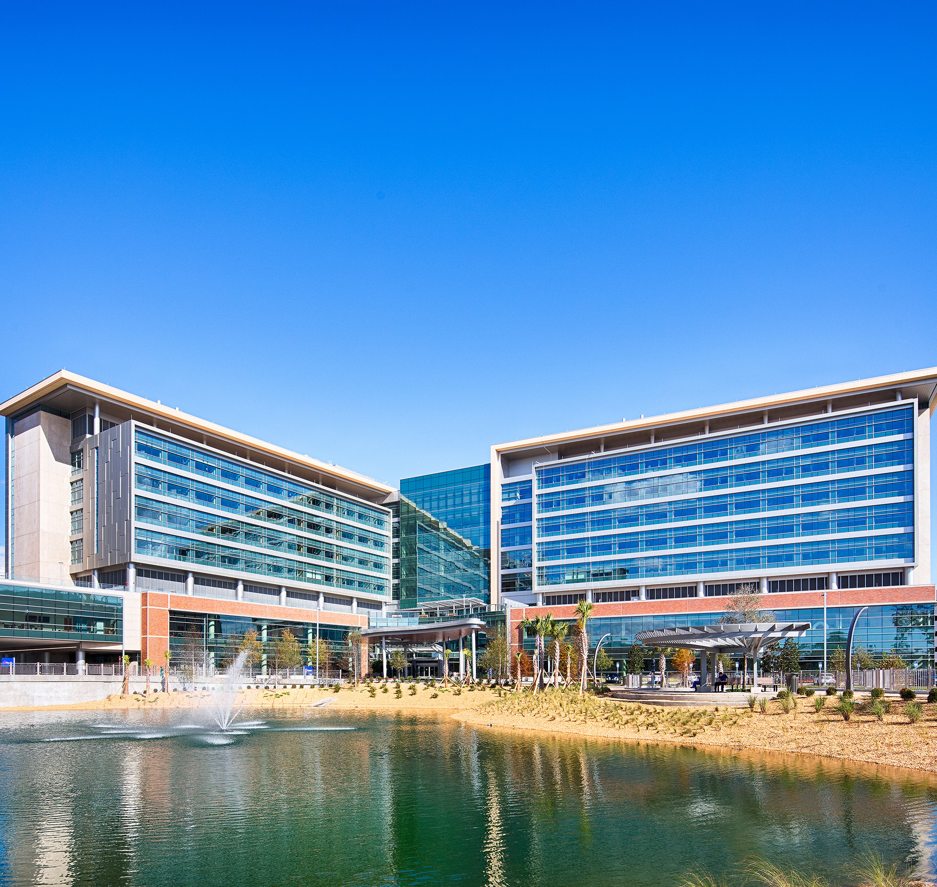 Modern Office Complex with Glass Facade by Scenic Water Pond Modern office buildings with glass facades reflecting a pond under a clear blue sky.