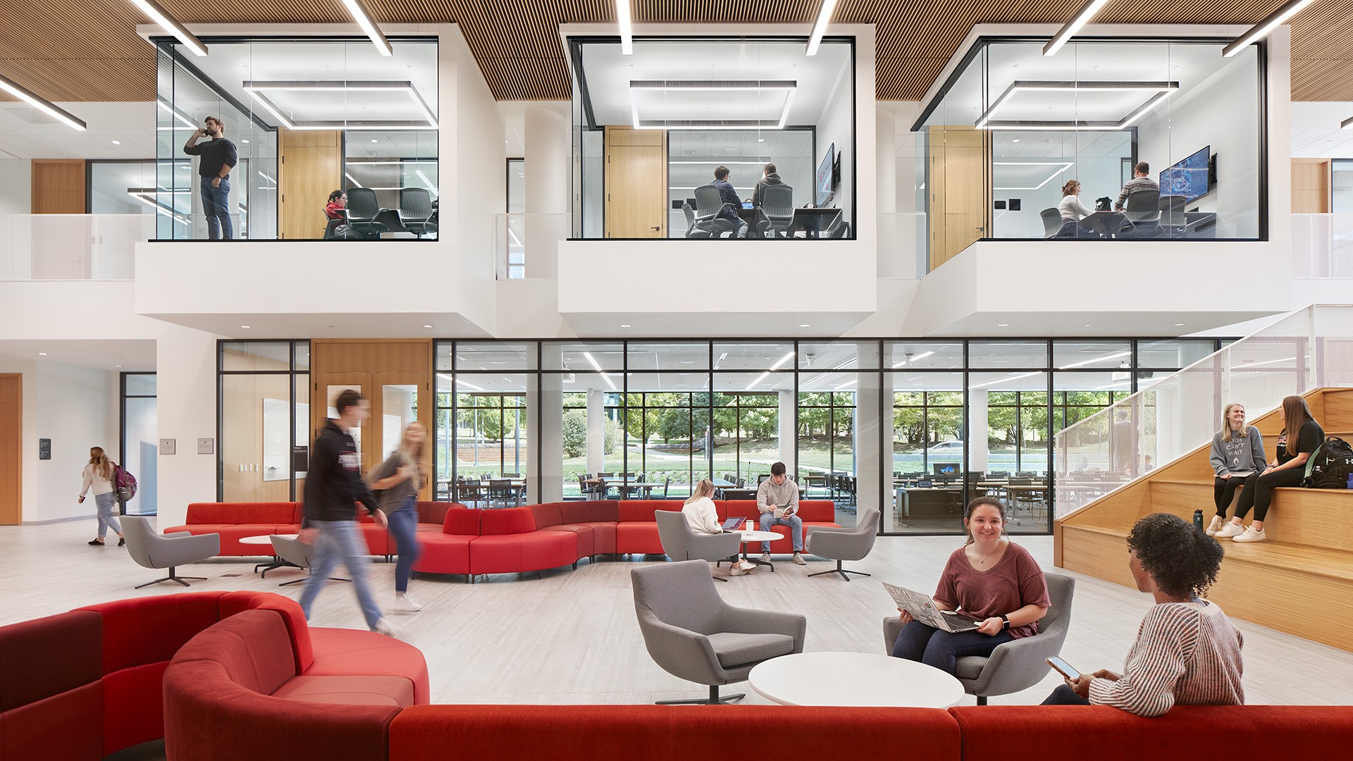 Students gather and move through a bright, modern university atrium filled with natural light and open study spaces.