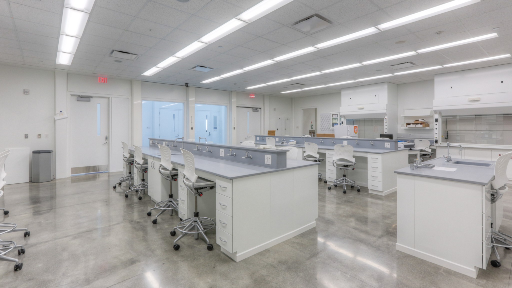 Modern, clean laboratory with white workbenches, chairs, and bright overhead lighting.