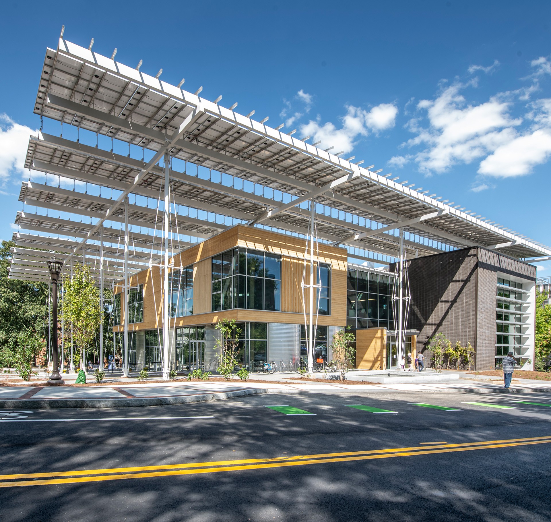 Modern Eco-Friendly Building with Solar Panel Canopy Design Modern building with large glass windows and solar panel canopy under a blue sky.