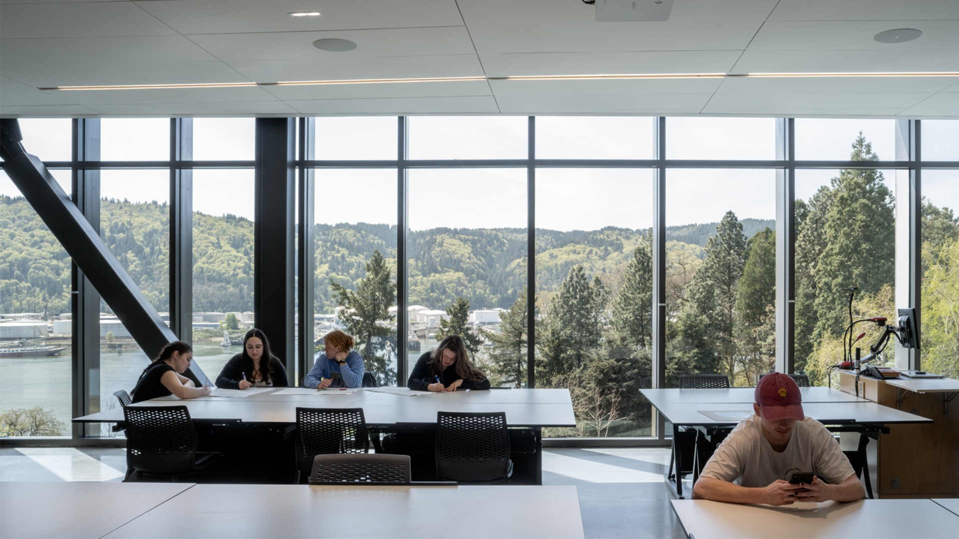 People working and using phones in a modern office with large windows and scenic view.