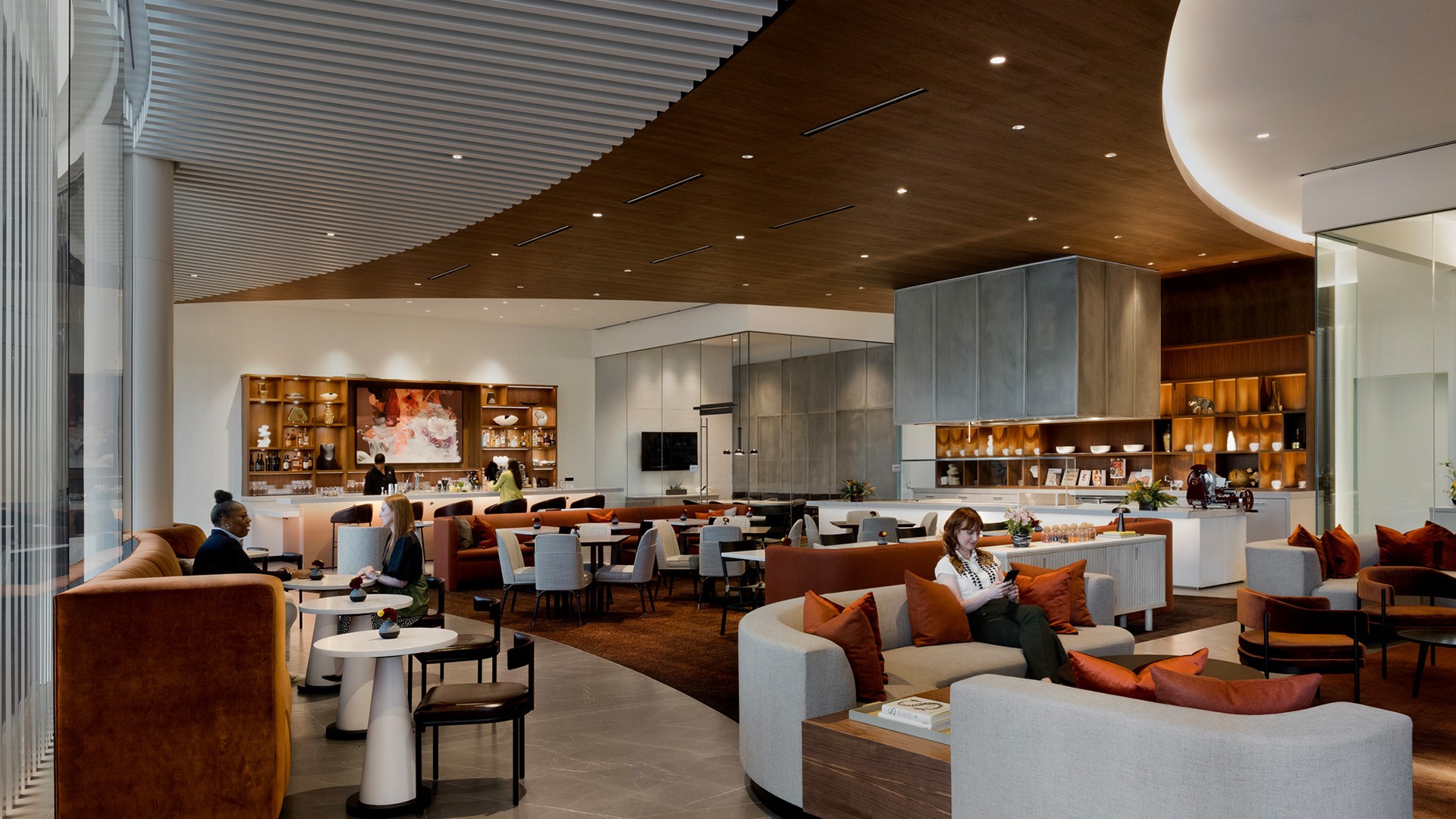 Modern, spacious lounge area with comfortable seating, warm lighting, and people relaxing.