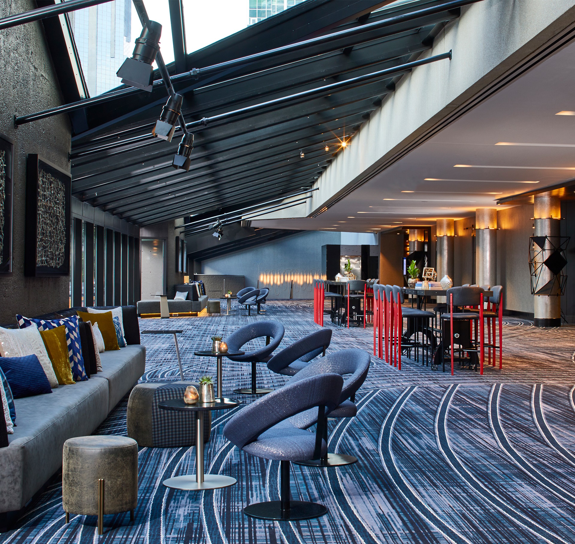 Modern Lounge Area with Stylish Seating and Natural Light Modern lounge area with blue chairs, patterned carpet, and large glass ceiling.