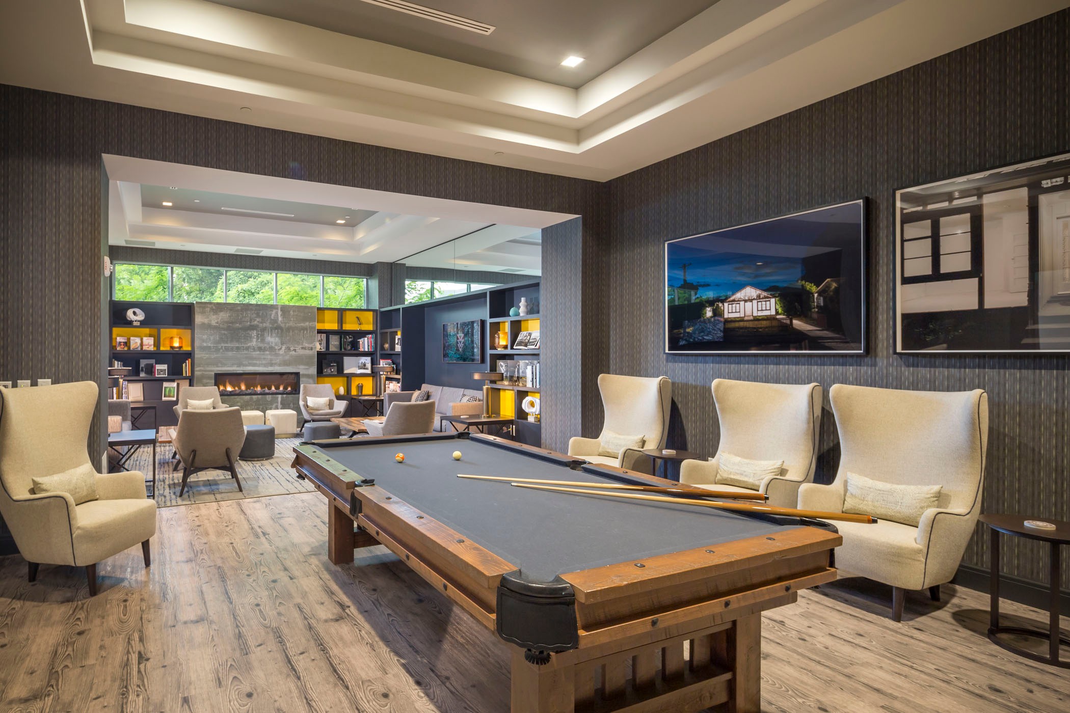 Modern lounge with a billiards table, cozy seating, and elegant decor featuring framed art.
