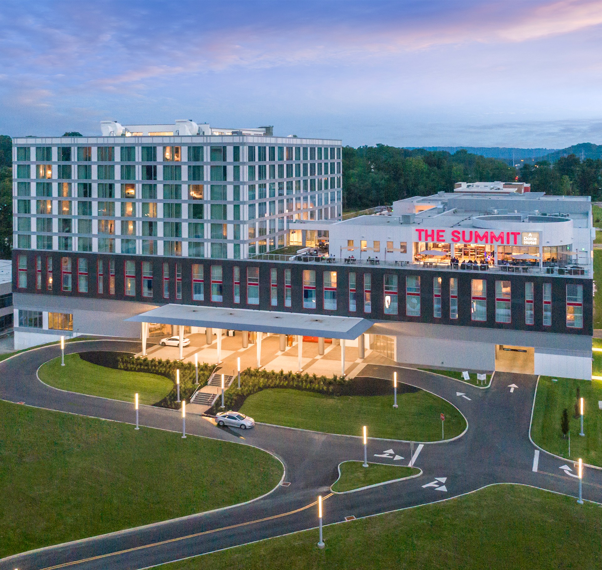 A modern hotel named "The Summit" with a sleek design, surrounded by greenery and a winding road.