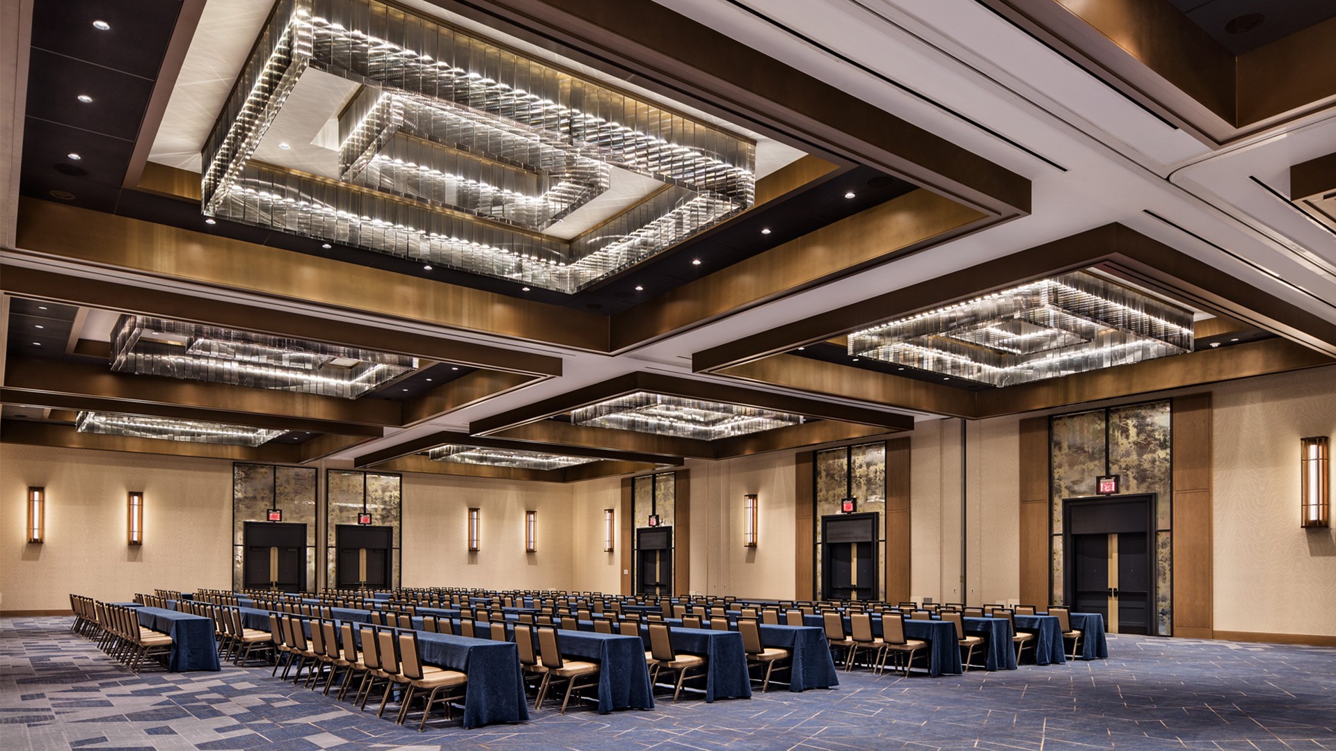 Spacious conference room with modern chandeliers and rows of chairs arranged for event.
