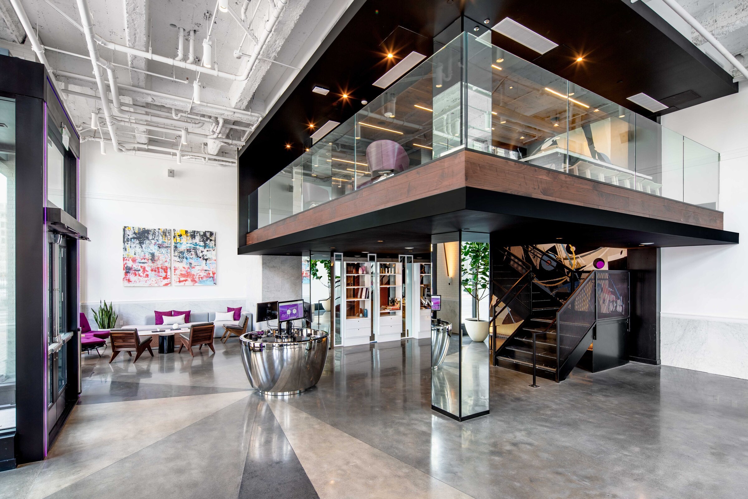 Modern lobby with sleek glass mezzanine, polished concrete floors, and contemporary seating.