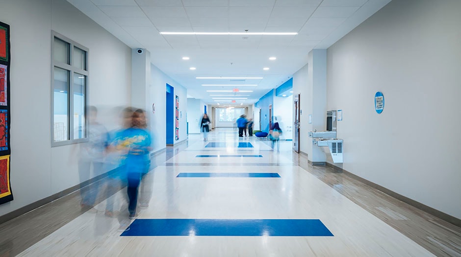 Modern school hallway with blurred motion of students walking, featuring bright blue accents.