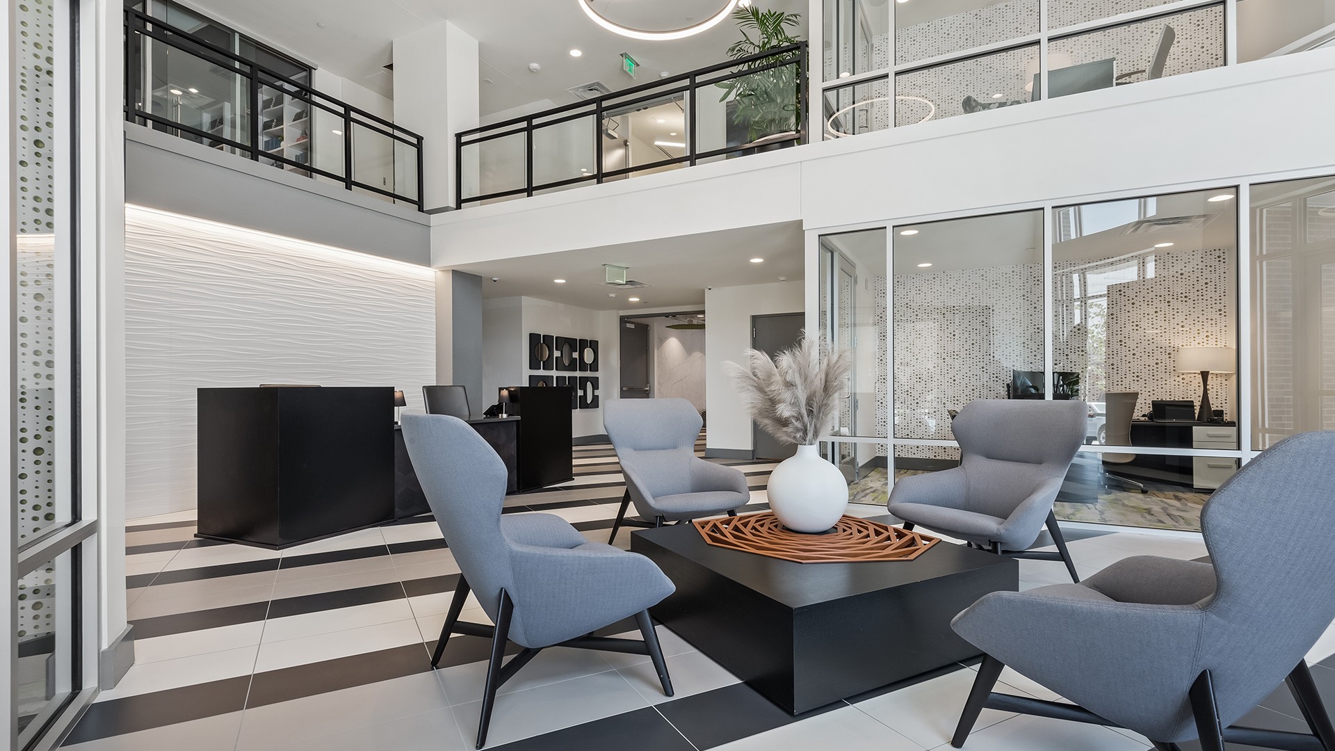 Modern Office Lounge Area with Stylish Seating and Decor Modern office lobby with stylish gray chairs, black table, and decorative vase centerpiece.