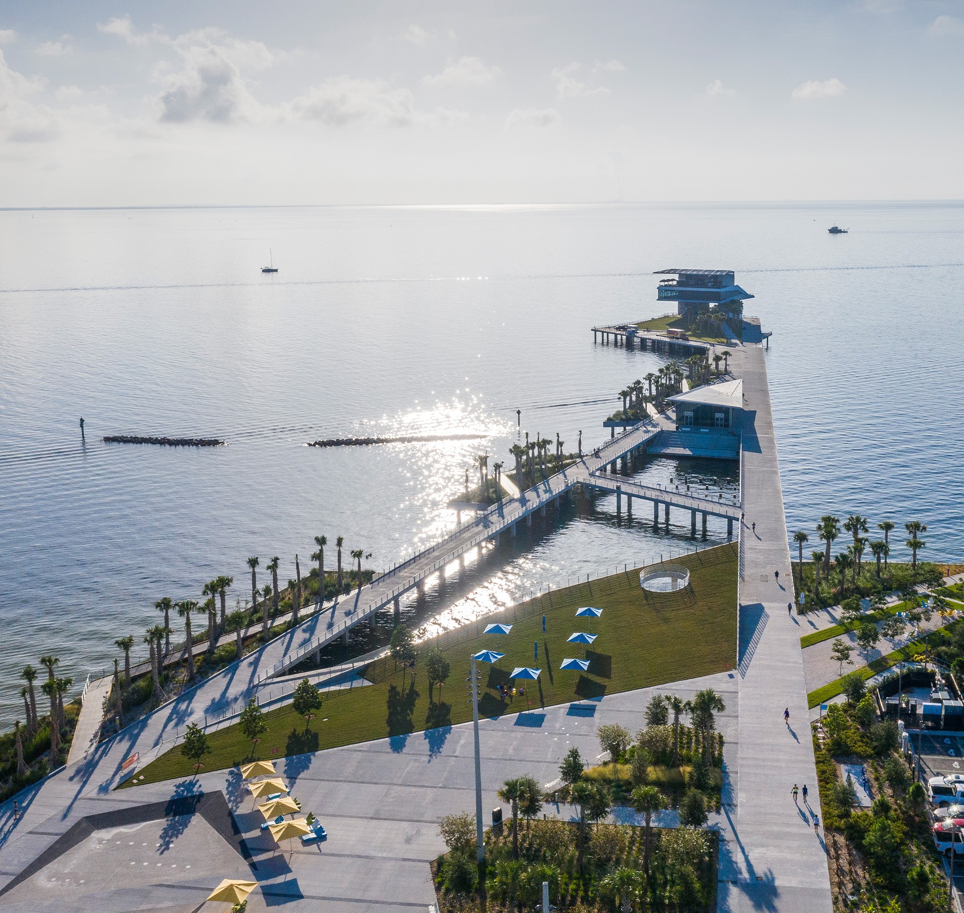 Modern pier with angular structures extending into the water, city skyline in the background.