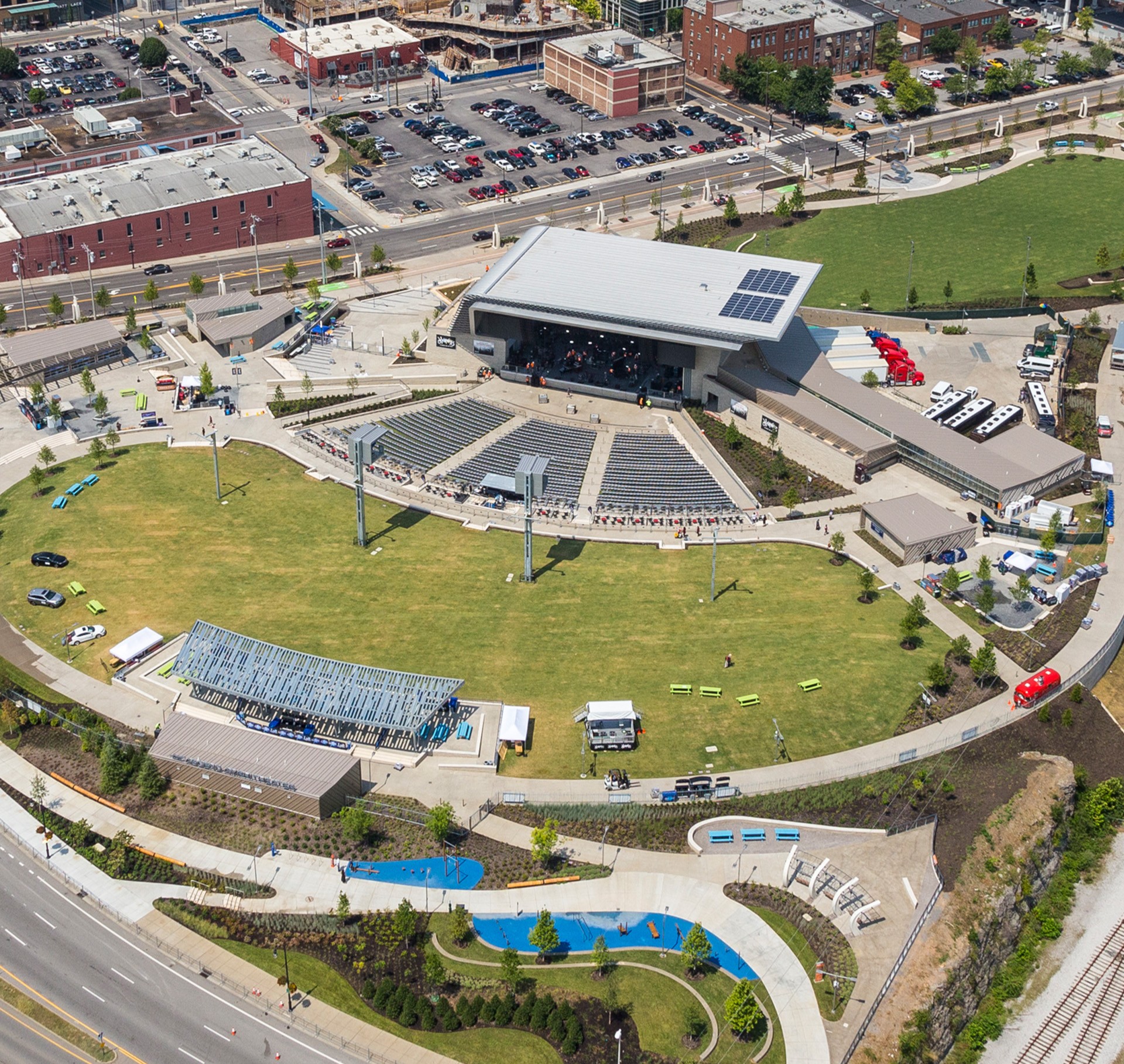 Aerial View of Outdoor Amphitheater with Green Park Space Aerial view of an outdoor amphitheater with stage, seating, and surrounding park area.