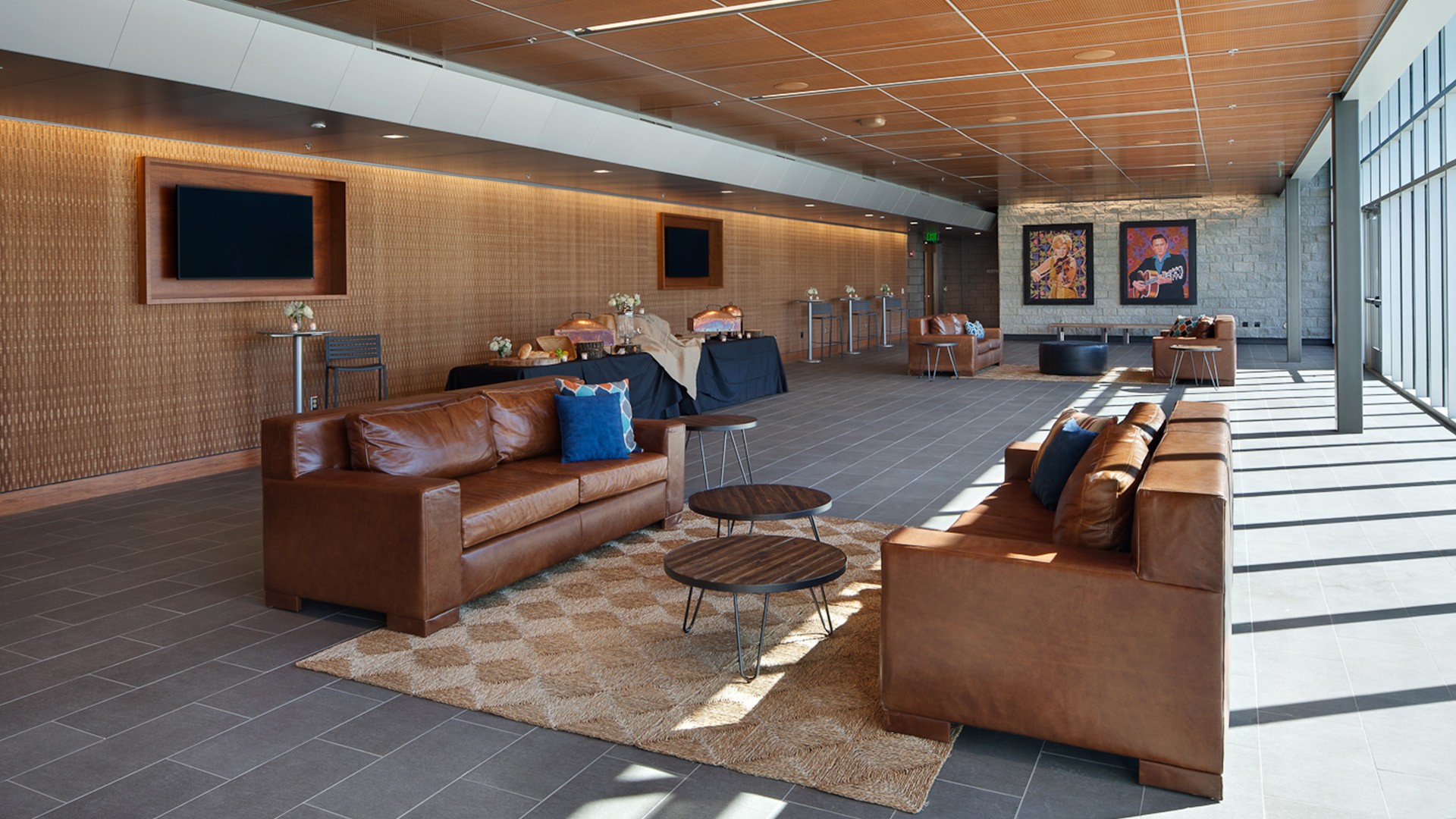 Modern lounge area with leather sofas and natural light Modern lounge area with brown leather sofas, wooden tables, and large windows.