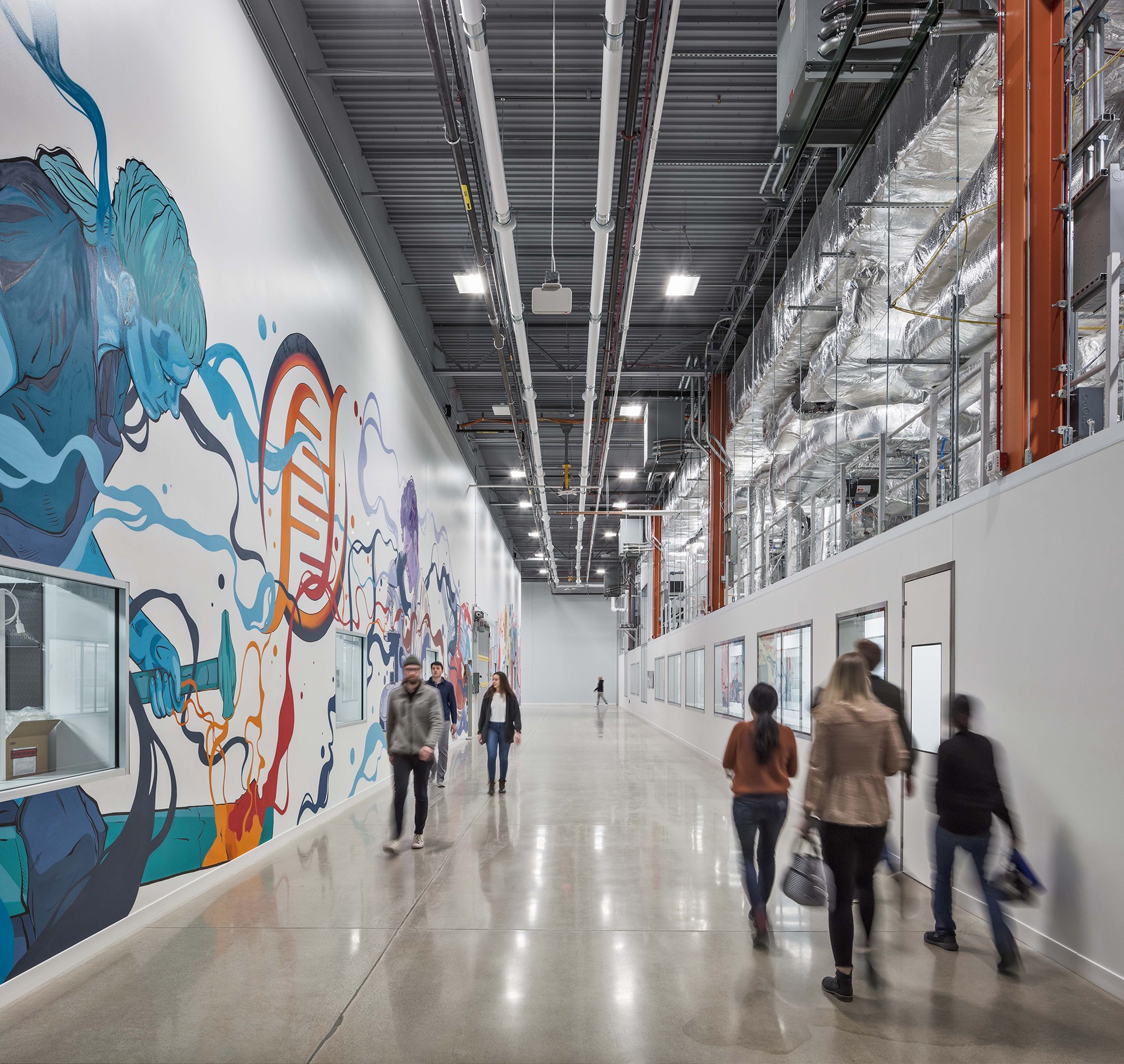 Modern Industrial Hallway with Colorful Wall Art and People Walking Modern industrial hallway with colorful mural and people walking inside a spacious building.