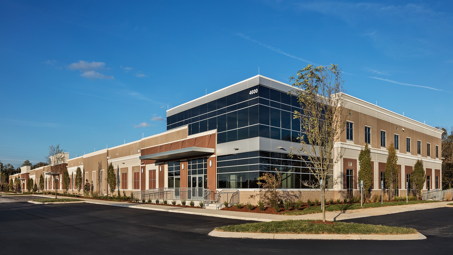 Modern Commercial Building Exterior with Clear Blue Sky Modern commercial building with glass and brick facade under clear blue sky.