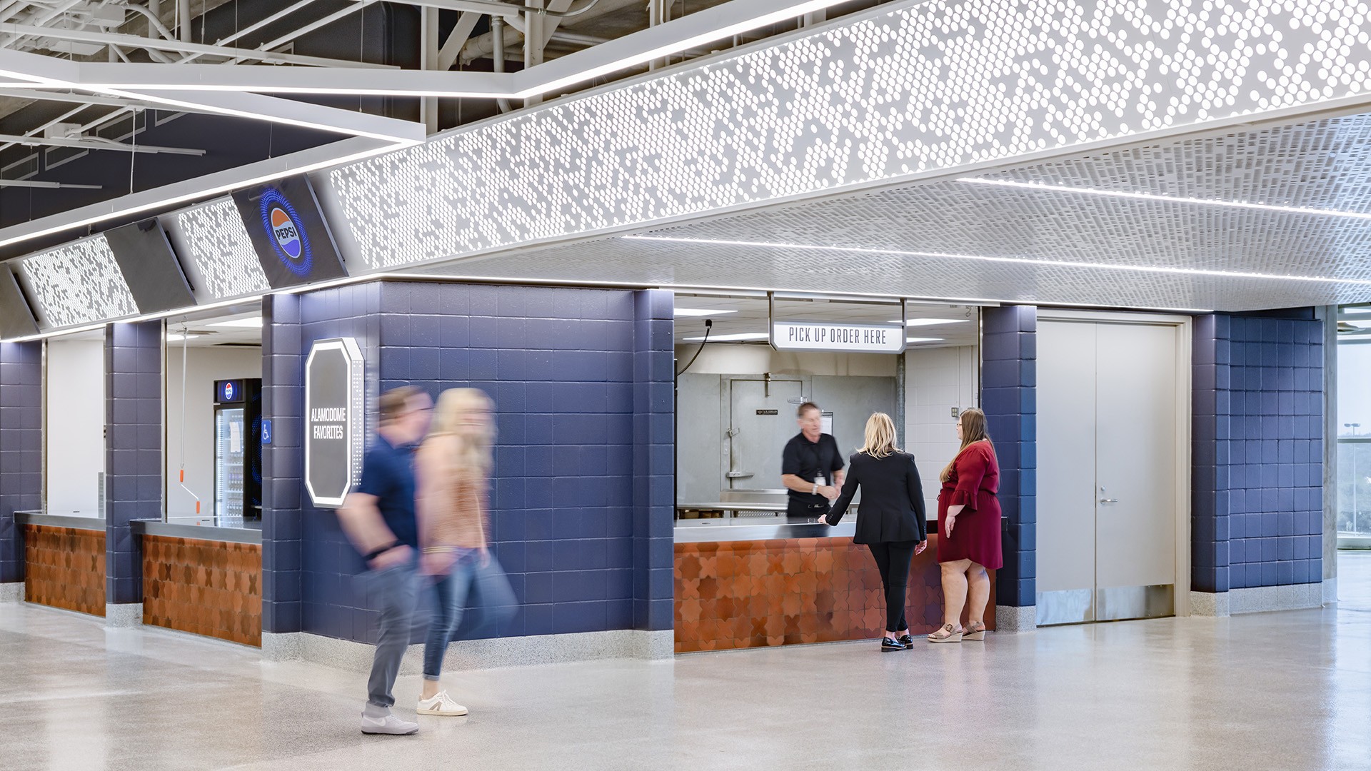 Modern food service counter with customers picking up orders in a bright indoor space.