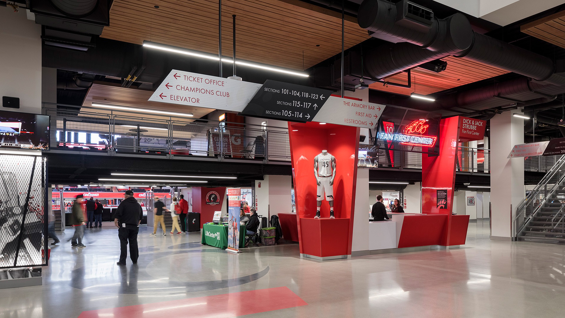 Interior view of a modern sports stadium concourse with signage and ticket counters.