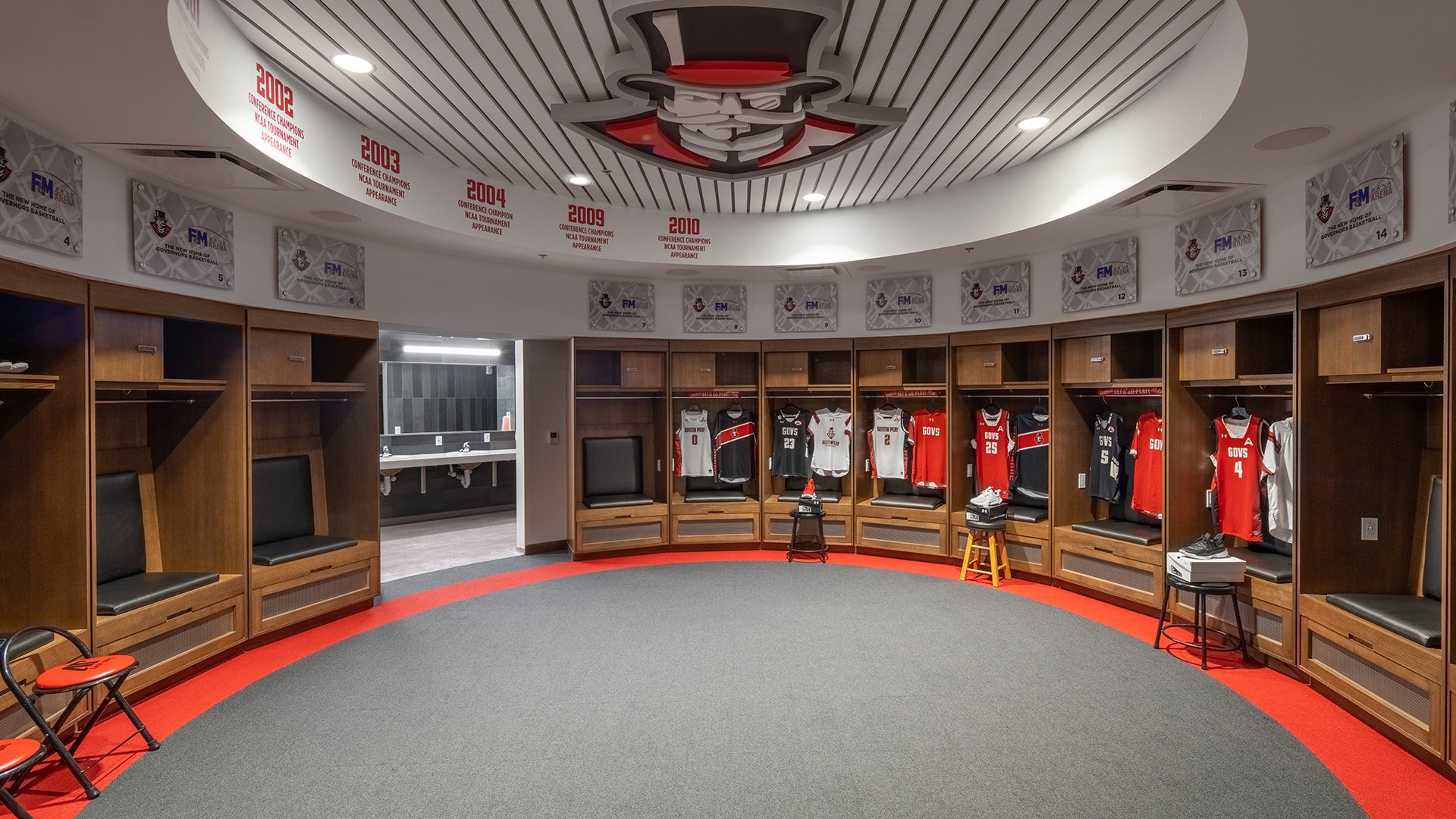 Modern basketball locker room with jerseys, wooden lockers, and circular ceiling design.