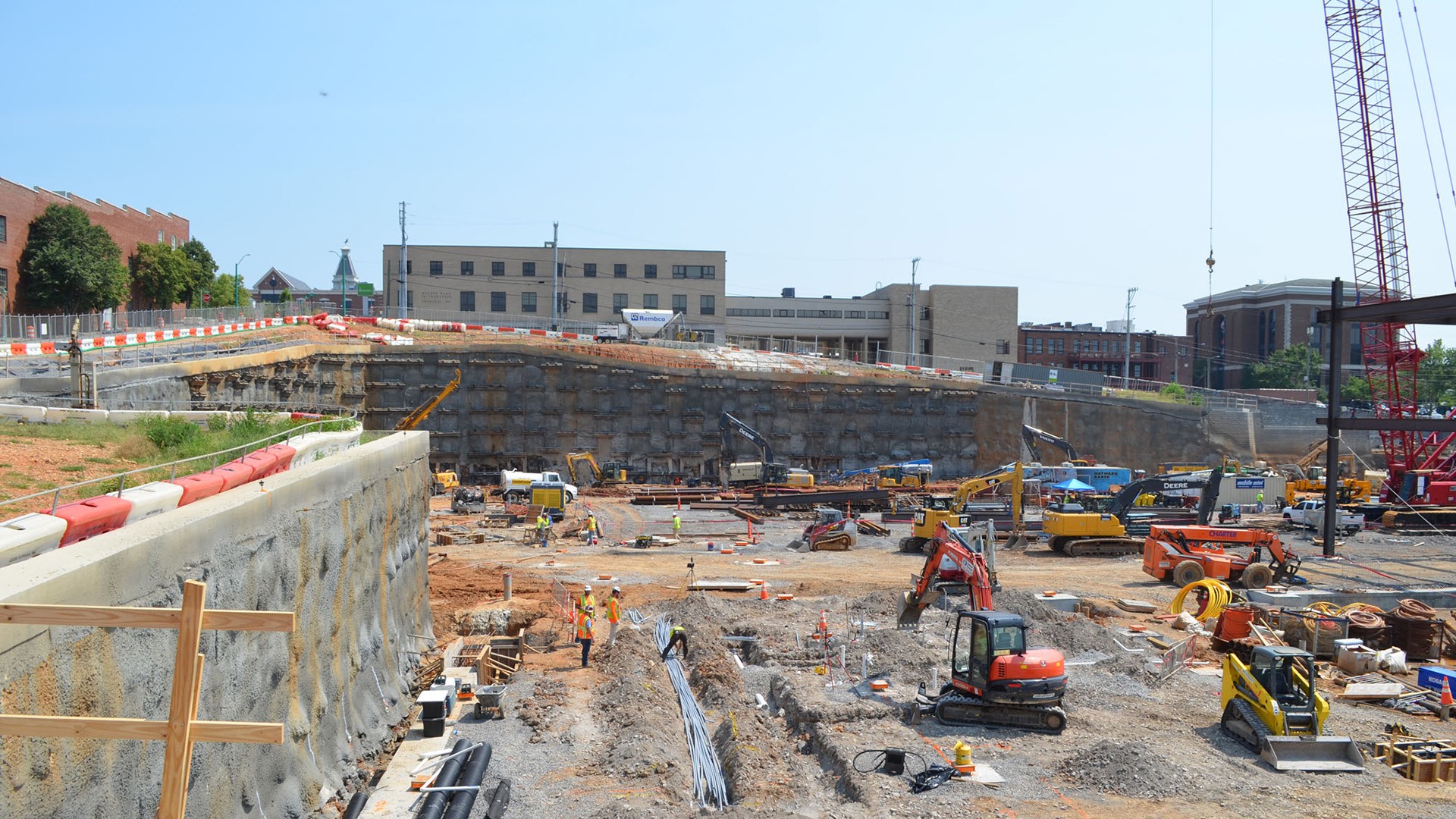 Construction site with heavy machinery and workers preparing foundation in urban area.
